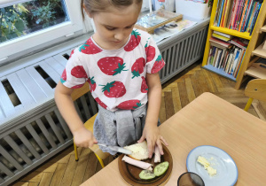 Na zdjęciu widzimy dziewczynkę, która samodzilnie smaruje sobie chleb masłem.