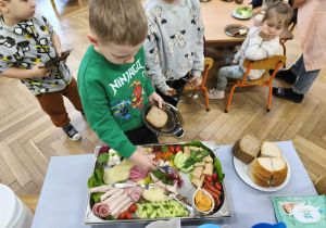 Na zdjęciu widzimy chłopca, który wybiera sobie produkty na śniadanie.