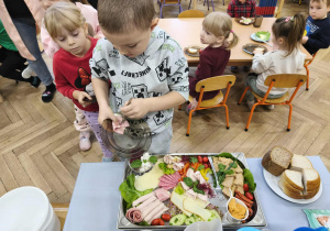 Na zdjęciu widzimy chłopca, który wybiera sobie produkty na śniadanie.