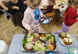 Na zdjęciu widzimy dziewczynkę, która wybiera sobie produkty na śniadanie.