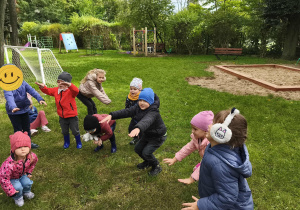 Na zdjęciu widzimy dzieci, które wykonują ćwiczenia ruchowe na dworze.