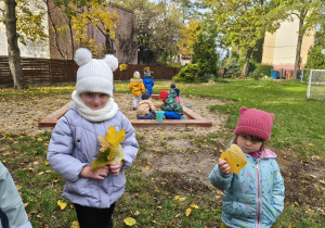 Na zdjęciu widzimy dziewczynki, które trzymają liście w rękach.