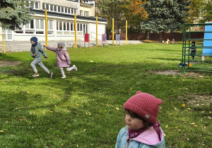 Na zdjęciu widzimy dzieci, które sowbodnie biegają po ogrodzie przedszkolnym.
