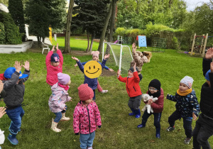 Na zdjęciu widzimy dzieci, które wykonują ćwiczenia ruchowe w ogordzie przedszkolnym.