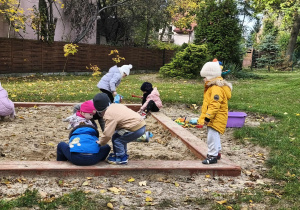 Na zdjęciu widzimy dzieci, które bawią się w piaskownicy przedszkolnej.