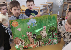 Dzieci pokaują obrazek leśnego świata - wyklejanka