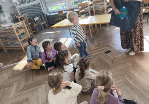 Prowadząca omawia z dziećmi temat pokazując ilustrację naszej planety