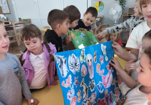 Dzieci pokaują obrazek morskiego świata - wyklejanka