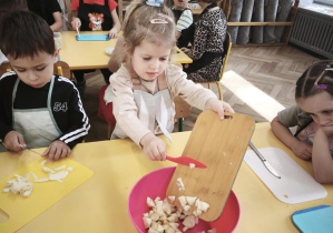 Dzieci wsypują pokrojone jabłka do miski