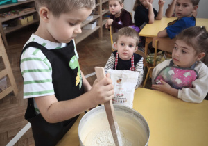 Dziecko miesza masę z mąką