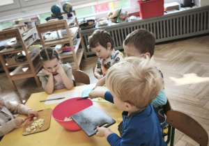 Dzieci wsypują pokrojone jabłka do miski