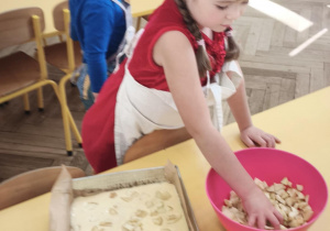 Dziecko układa jabłka na cieście