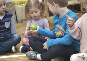 Dzieci wąchają i oglądają jabłko