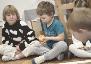 Dzieci wąchają i oglądają jabłko