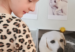 Dziewczynka przywiesza na tablicy zdjęcie swojego psa.