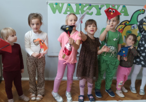 Dzieci stoją i pokazują zrobione przez siebie papierowe pieski.