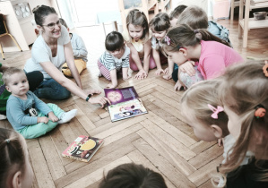 Dzieci oglądają ilustracje w książce.