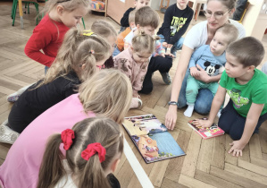 Dzieci oglądają ilustracje w książce.