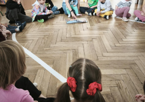 Mama czytająca książkę przedszkolakom siedzący w kole.