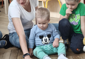 Mama czytająca książkę przedszkolakom siedzący w kole.