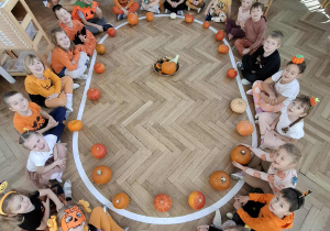 dzieci siedzą na elipsie przed każdym leży dynia