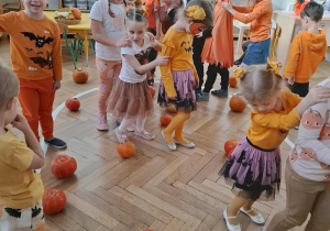 dzieci maszerują między dyniami