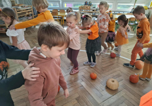 dzieci maszerują między dyniami