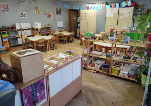 na zdjęciu znajduje się sala grupy piątej, niskie stoliki i regały, na których znajdują sie pomoce rozwojowe dla dzieci,