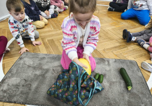 Na zdjęciu widzimy dziewczynkę, która z torby wyjmuje melona.