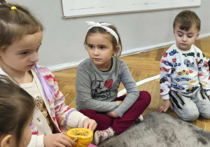 Na zdjęciu widzimy dziewczynki, które wąchają i obserwują co znajduje się w dyni ozdobnej.