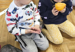 Na zdjęciu widzimy dziewczynkę, która wącha dynię ozdobną - dynię mini.