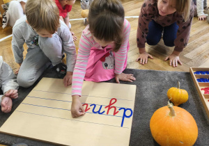 Na zdjęciu widzimy dziewczynkę, która z ruchomego alfabetu wyszukała głoskę "i".