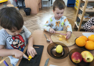 Na zdjęciu widzimy dwóch chłopców, którzy kroją dynię.