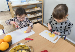 Na zdjęciu widzimy dwie dziewczynki, które kroją kawałki dyni.