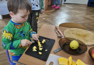 Na zdjęciu widzimy chłopca, który kroi na kawałki dynię.