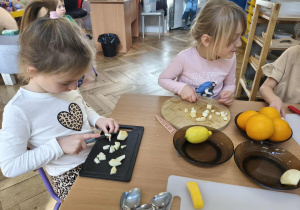 Na zdjęciu widzimy dziewczynki, które kroją kawałki jabłka.
