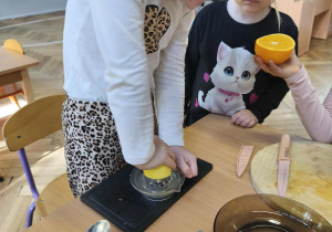 Na zdjęciu widzimy dziewczynkę, która wyciska cytrynę.