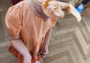 Na zdjęciu widzimy dziewczynkę, która trzyma w ręku ilustrację dyni znalezioną podczas zabawy "Szukam dyni".