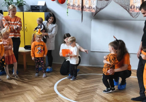 Na zdjęciu widzimy chłopca, który trzyma dyniowe wiaderko. Chłopiec uczestniczy w zabawie "Cukierek albo psikus".