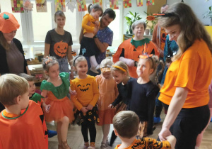 Na zdjęciu widzimy grupkę dzieci oraz rodzica, który pokazuje figurę do wykonania.