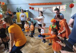 Na zdjęciu widzimy grupkę dzieci oraz rodzica, który pokazuje figurę do wykonania.