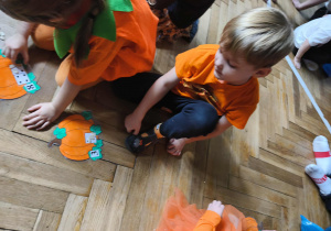 Na zdjęciu widzimy dzieci, które uczestniczą w zabawie "Liczymy pestki dyni".