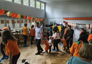 Na zdjęciu widzimy dzieci oraz ich rodziców, który uczestniczą w zabawie "Dyniowy pociąg".