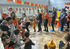 Na zdjęciu widzimy dzieci oraz ich rodziców, który uczestniczą w zabawie "Dyniowy pociąg".