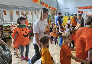 Na zdjęciu widzimy dzieci oraz ich rodziców, który uczestniczą w zabawie "Dyniowy pociąg".