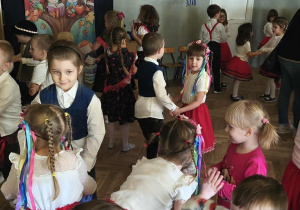 Na zdjęciu widzimy grupkę dzieci uczestniczących w tańczach i zabawach do muzyki ludowej.