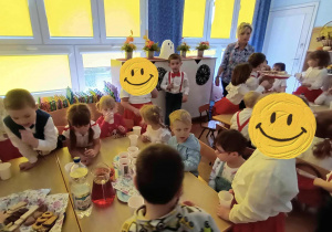 Na zdjęciu widzimy dzieci częstujące się ciastkami i napojami.