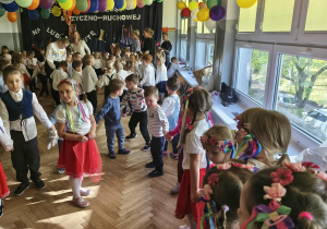 Na zdjęciu widzimy grupkę dzieci uczestniczących w tańczach i zabawach do muzyki ludowej.