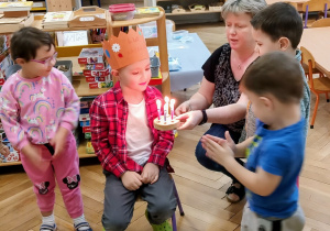 Chłopiec zdmuchuje świeczki na symbolicznym torcie.