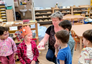 Chłopiec zdmuchuje świeczki na symbolicznym torcie.